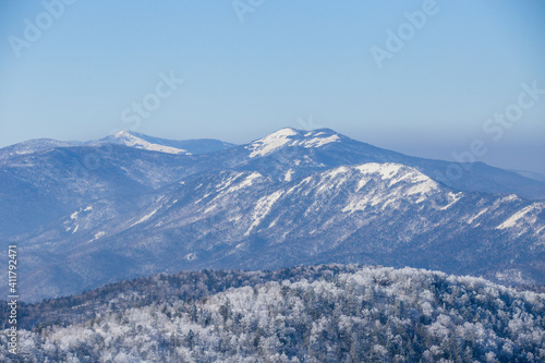 Beautiful winter landscape. The peaks of the snow-capped mountains are buried in morning fog.