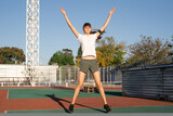 Teenager girl working out at the stadium doing jumping jacks