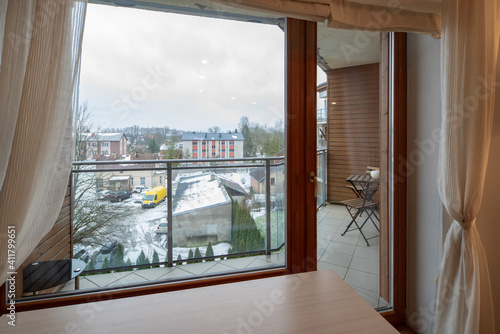 Modern interior of luxury apartment. Window and glass door to balcony. View of city.