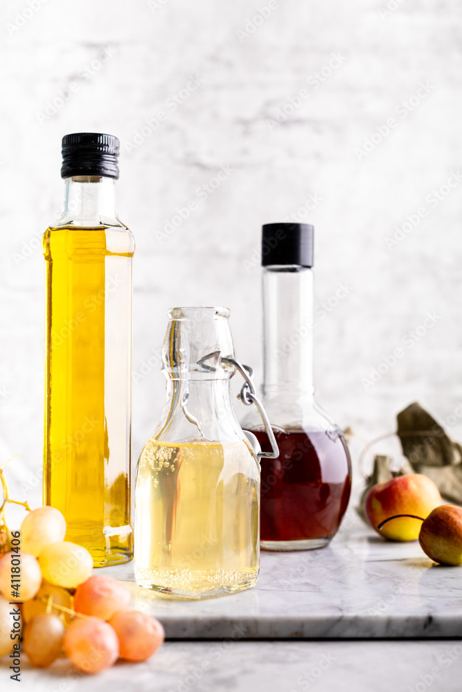 Original glass bottles with different vinegar on a marble table against a background of a white brick wall. Copy space. Original glass bottles with different vinegar on a marble table against a background of a white brick wall. Copy space.