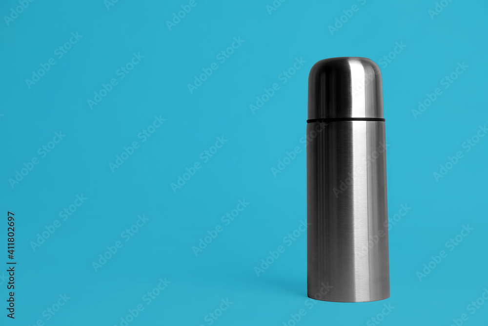 Stylish thermo bottle on light blue background, space for text Stylish thermo bottle on light blue background, space for text