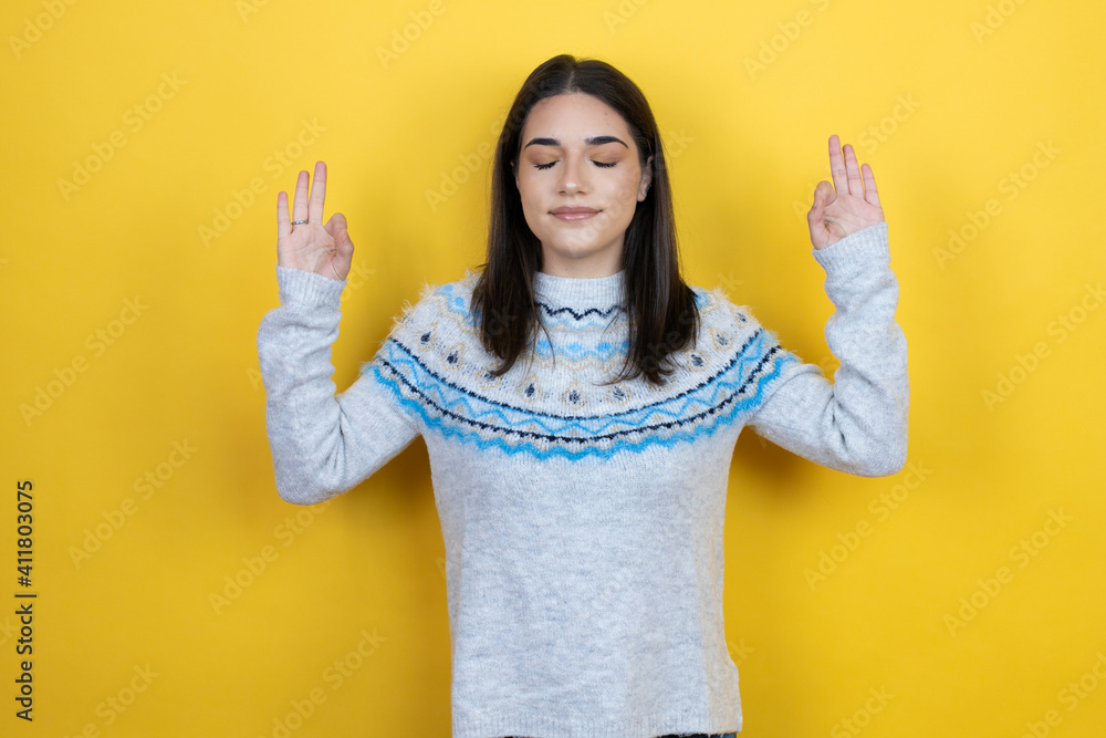 Young caucasian woman wearing casual sweater over yellow background relax and smiling with eyes closed doing meditation gesture with fingers Young caucasian woman wearing casual sweater over yellow background relax and smiling with eyes closed doing meditation gesture with fingers