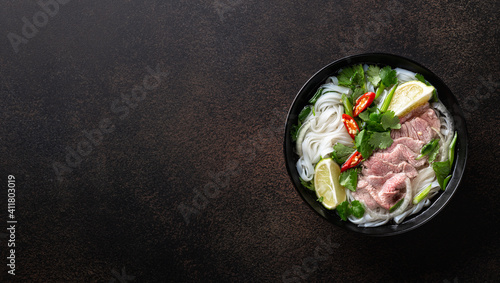 Pho Bo vietnamese soup with beef and rice noodles on a dark background, top view, copy space
