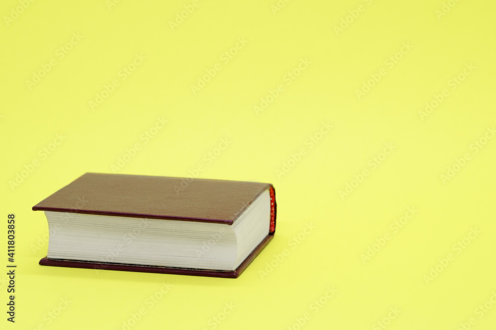 Thick old book on yellow background. Space for text. Concept: education, session, love of literature, reading, knowledge Thick old book on yellow background. Space for text. Concept: education, session, love of literature, reading, knowledge