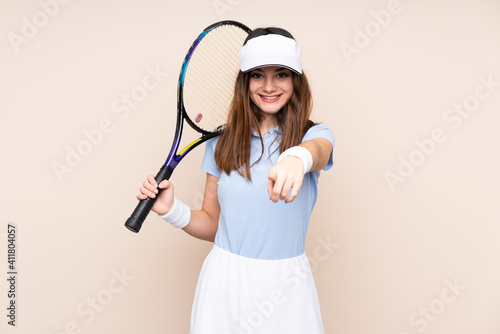 Young caucasian woman isolated on beige background playing tennis and pointing to the front © luismolinero