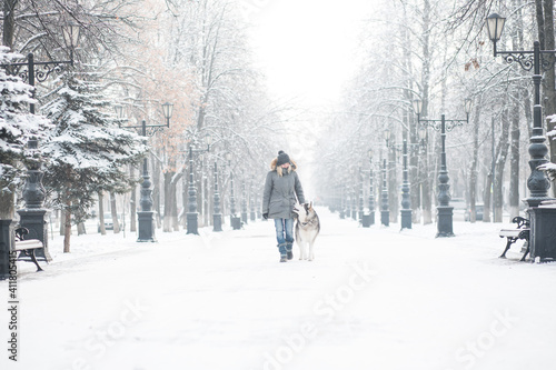 European woman walking with Alaskan malamute dog in winter city.  © Iulia