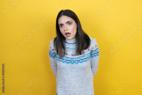 Young caucasian woman wearing casual sweater over yellow background afraid and shocked with surprise and amazed expression, fear and excited face. © Irene