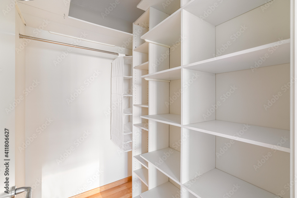 Interior of small, white and empty dressing room with shelves and no clothes Interior of small, white and empty dressing room with shelves and no clothes