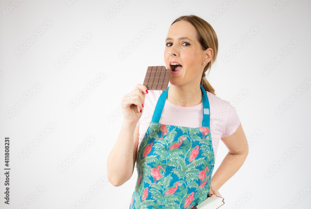 Smiling beautiful young woman wearing apron hold chocolate bar over white background. Smiling beautiful young woman wearing apron hold chocolate bar over white background.