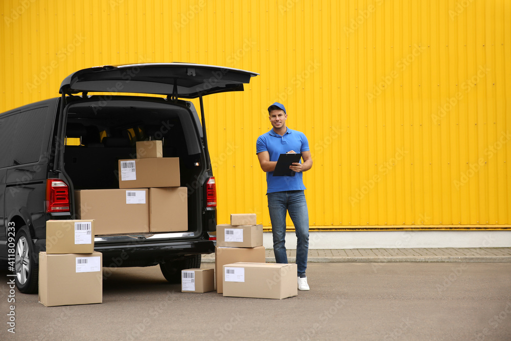Courier with clipboard and parcels near delivery van outdoors Courier with clipboard and parcels near delivery van outdoors