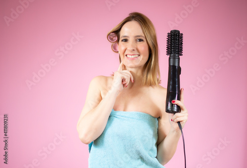 Portrait of young beautiful woman doing hairstyle over pink background.