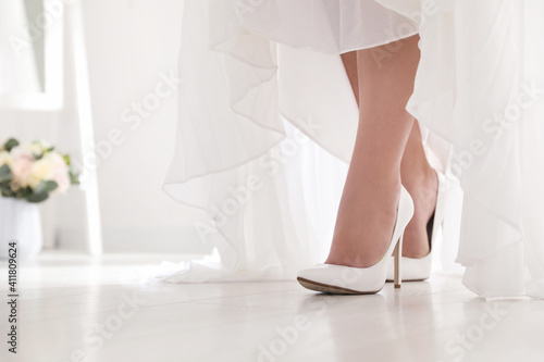 Young bride in beautiful wedding shoes walking indoors, closeup © New Africa