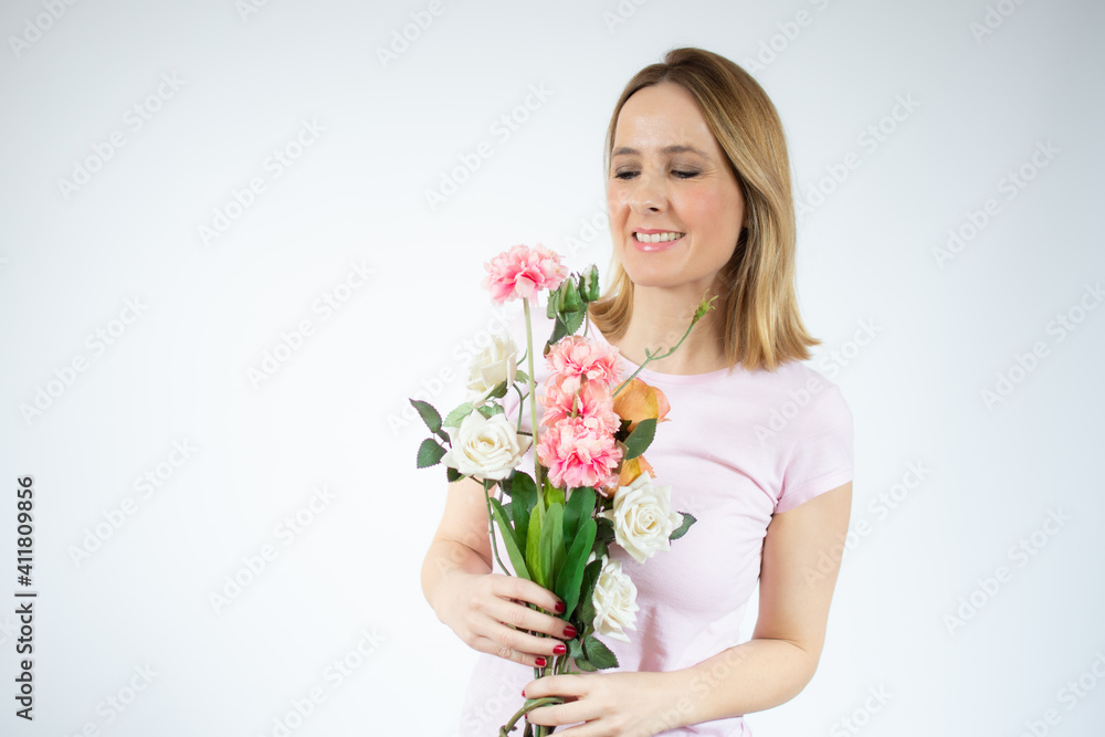 Portrait of a beautiful young woman in casual t-shirt holding big bouquet of flowers isolated over white background