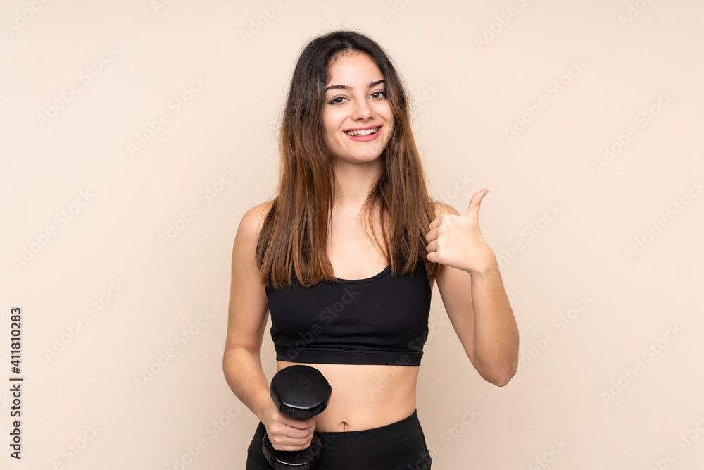 Young sport woman making weightlifting isolated on beige background giving a thumbs up gesture Young sport woman making weightlifting isolated on beige background giving a thumbs up gesture