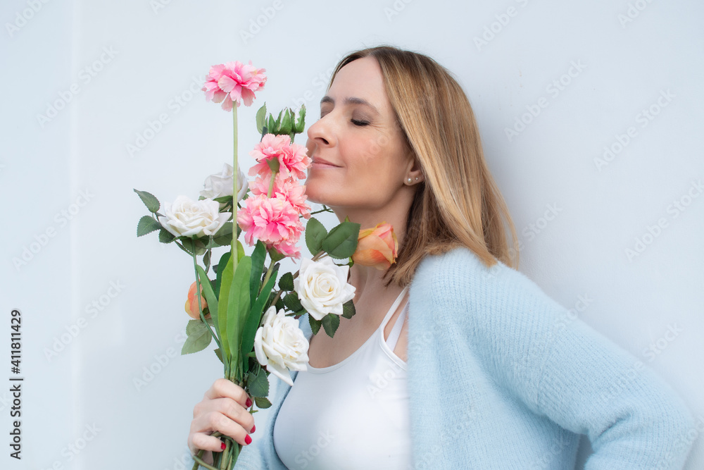 Happy woman wearing blue sweater holding flowers outdoors