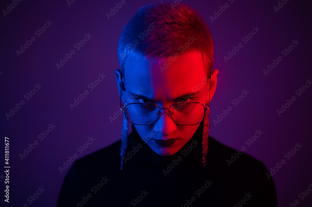 Portrait of a beautiful young woman with short hair in neon light. Displeased girl posing Portrait of a beautiful young woman with short hair in neon light. Displeased girl posing