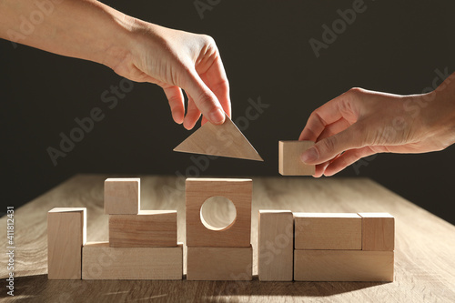 Billede på lærred People constructing with wooden building blocks, closeup