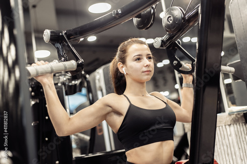 Young sporty woman exercising her back in lat exercise machine in modern gym