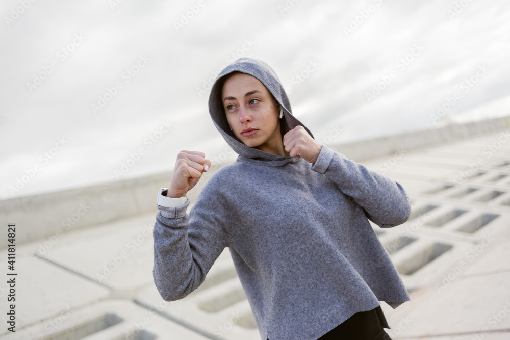 Sporty woman fighter stands in a fighting stance outdoors