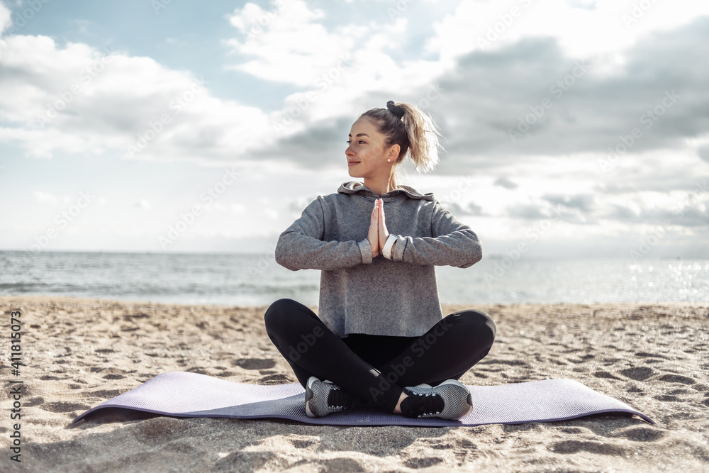 Attractive fit woman in sportswear meditates on the beach on a bright sunny day Attractive fit woman in sportswear meditates on the beach on a bright sunny day