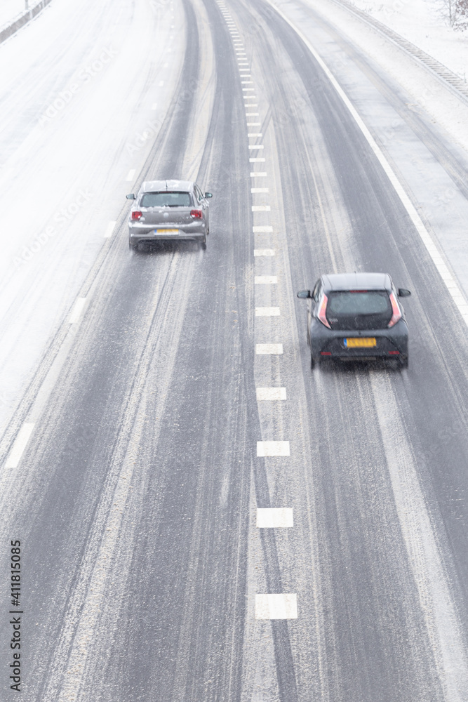 Snowy highway with a lonely car traveling through blizzard Snowy highway with a lonely car traveling through blizzard