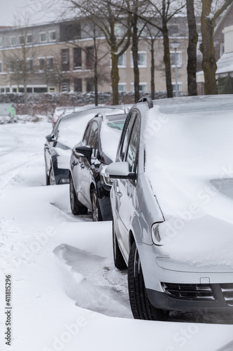 Cars parked in a street in a modern suburb covered with snow after a snow storm photo