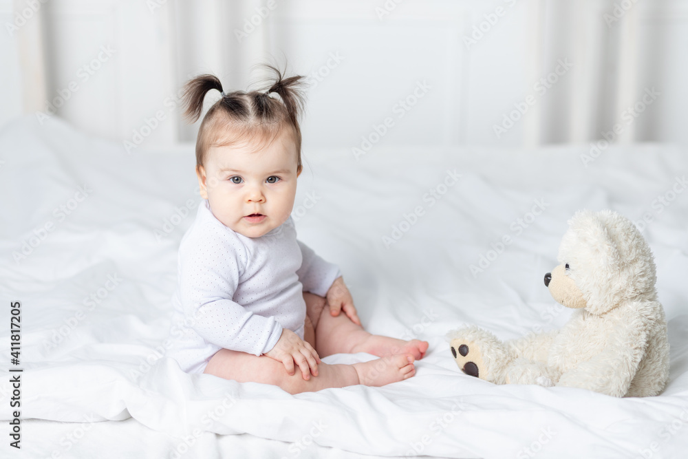 baby girl playing with a teddy bear toy on the bed at home, the concept of play and development of children baby girl playing with a teddy bear toy on the bed at home, the concept of play and development of children