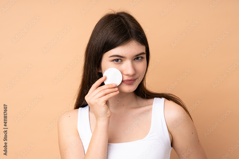 Young Ukrainian teenager girl over isolated background with cotton pad for removing makeup from her face Young Ukrainian teenager girl over isolated background with cotton pad for removing makeup from her face