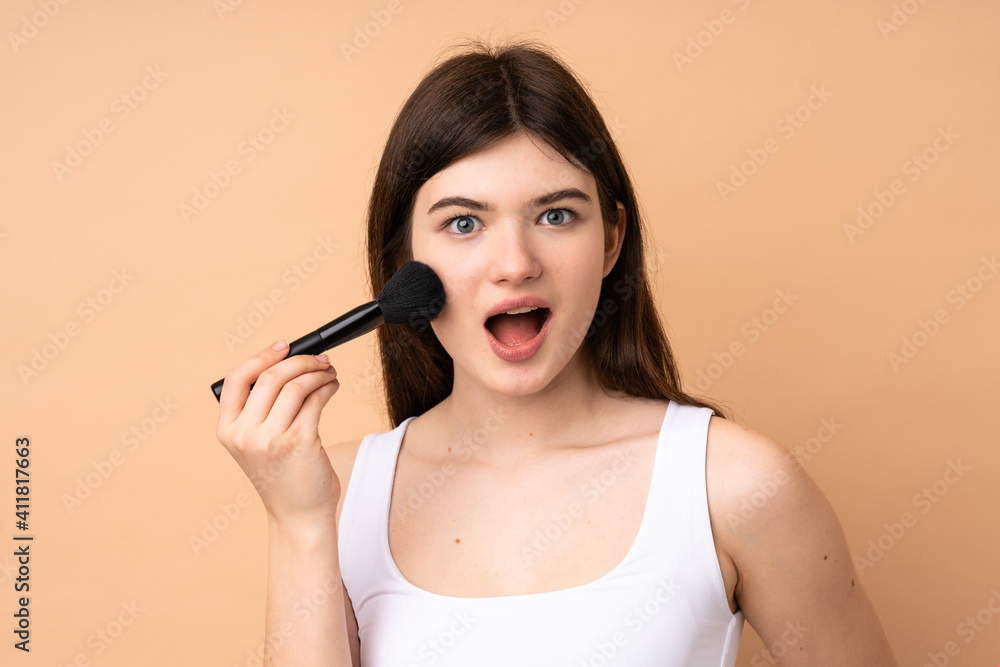 Young Ukrainian teenager girl over isolated background holding makeup brush and surprised Young Ukrainian teenager girl over isolated background holding makeup brush and surprised