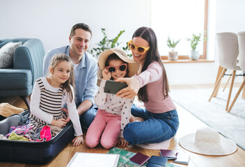 Parents with small daughters indoors at home, packing for summer holiday.