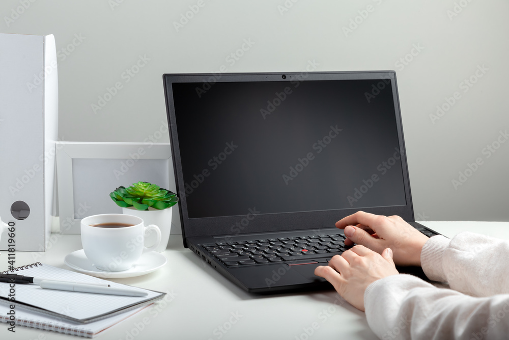 Woman works on laptop in online education on workspace. Female hands typing on laptop. Black laptop display Mock up blank. Workplace in home office for remote work minimal style on white background Woman works on laptop in online education on workspace. Female hands typing on laptop. Black laptop display Mock up blank. Workplace in home office for remote work minimal style on white background
