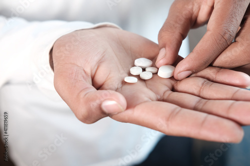 man's hand with medicine spilled out of the pill container 