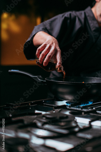 unrecognizable chef pouring oil into frying pan