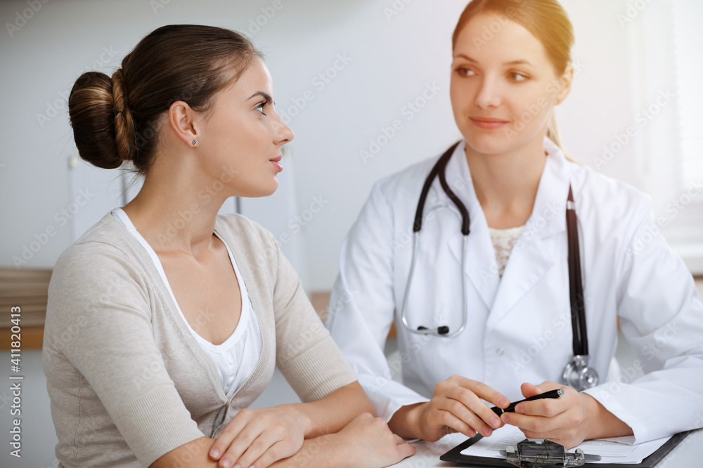 Doctor and patient sitting and discussing health examination results in sunny clinic office Doctor and patient sitting and discussing health examination results in sunny clinic office