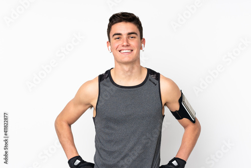 Teenager sport man over isolated white wall posing with arms at hip and smiling