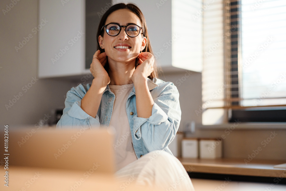 Happy charming woman smiling while working with laptop at home Happy charming woman smiling while working with laptop at home