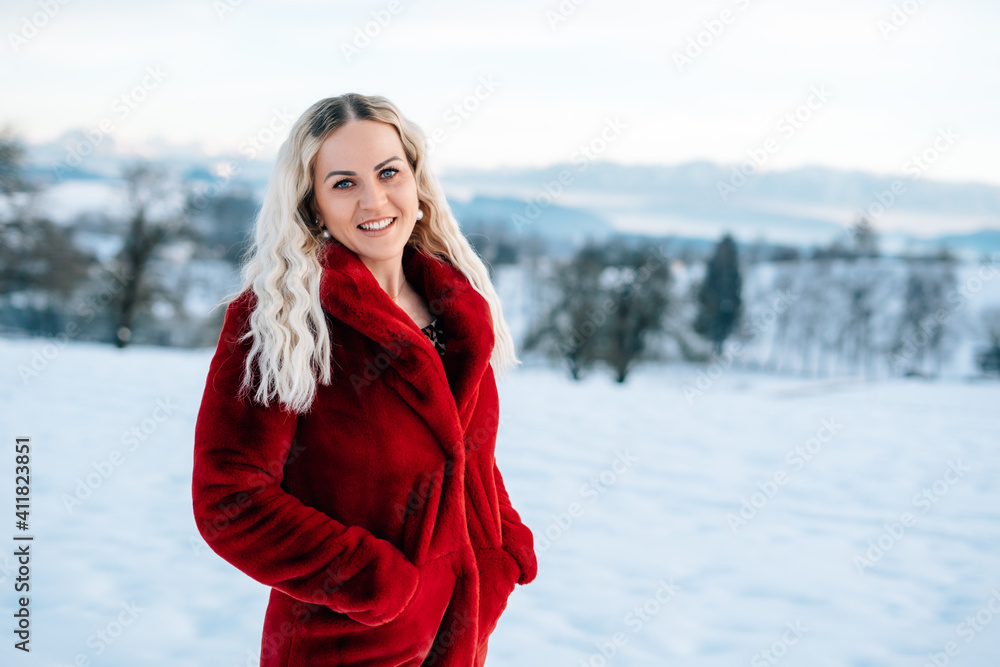 Frau im Schnee mit rotem Mantel lacht blonde lockige Haare Freude Winterlandschaft stapft durch den Schnee