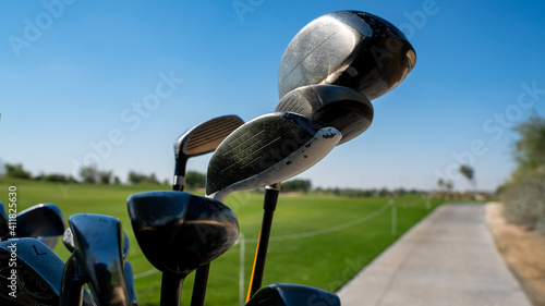 Background image of multiple golf sticks on the behind of a golf cart.
