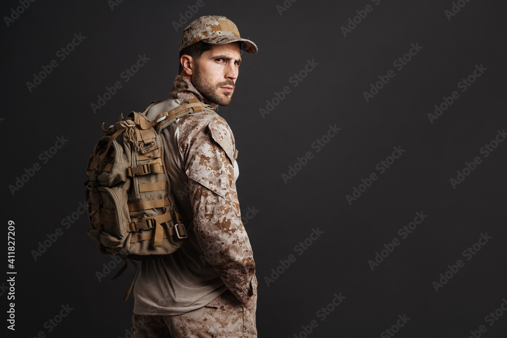 Confident masculine military man in uniform posing with backpack Confident masculine military man in uniform posing with backpack