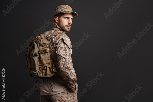 Confident masculine military man in uniform posing with backpack © Drobot Dean