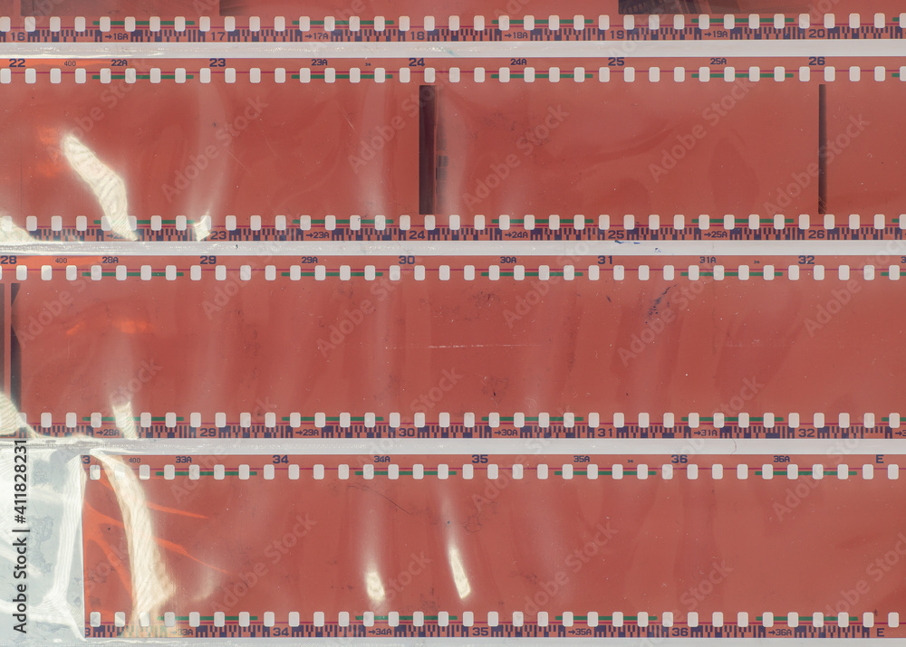 film camera with broken shutter produced blank or underexposed negatives. 35mm film material on white background behind foil. film camera with broken shutter produced blank or underexposed negatives. 35mm film material on white background behind foil.