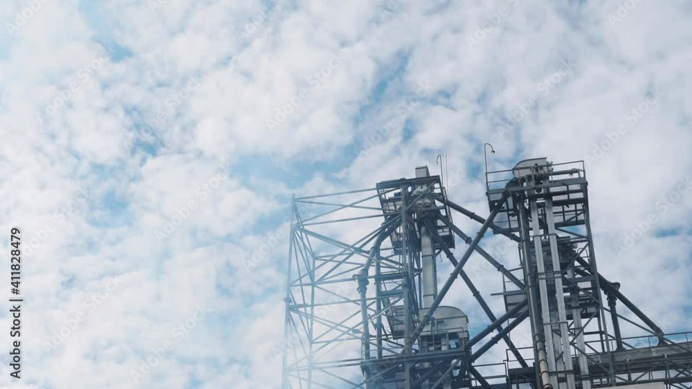 Ecological problems. High construction of a factory in the sky. White steam near the metal construction of a large manufacturing. Ecological problems. High construction of a factory in the sky. White steam near the metal construction of a large manufacturing.