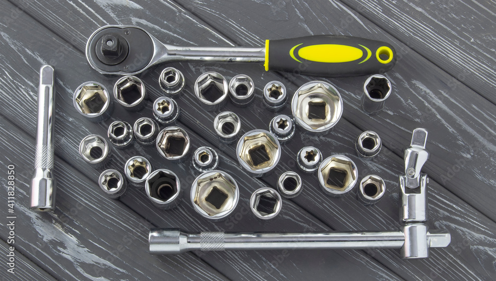 Interchangeable nozzles with a ratchet key on a gray wooden background. Interchangeable nozzles with a ratchet key on a gray wooden background.