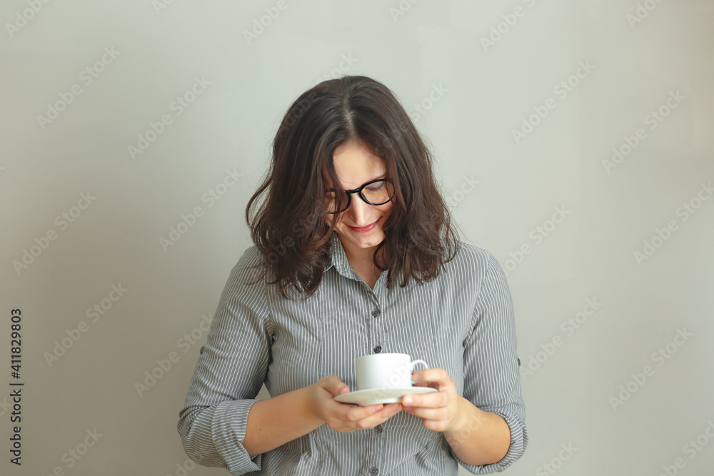 Smiling brunette business Woman or student Holding Coffee Cup Against gray Background isolated Smiling brunette business Woman or student Holding Coffee Cup Against gray Background isolated