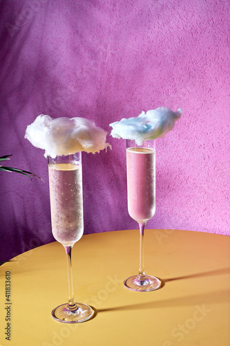 champagne in a glass decorated with a cloud on a pink background.

