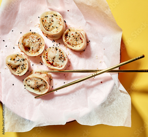 delikatne pierożki japoskie posypane ziarnami z  drewnianymi pałeczkami do jedzenia 