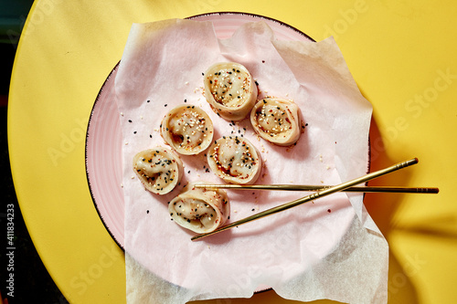 delikatne pierożki japoskie posypane ziarnami z  drewnianymi pałeczkami do jedzenia 