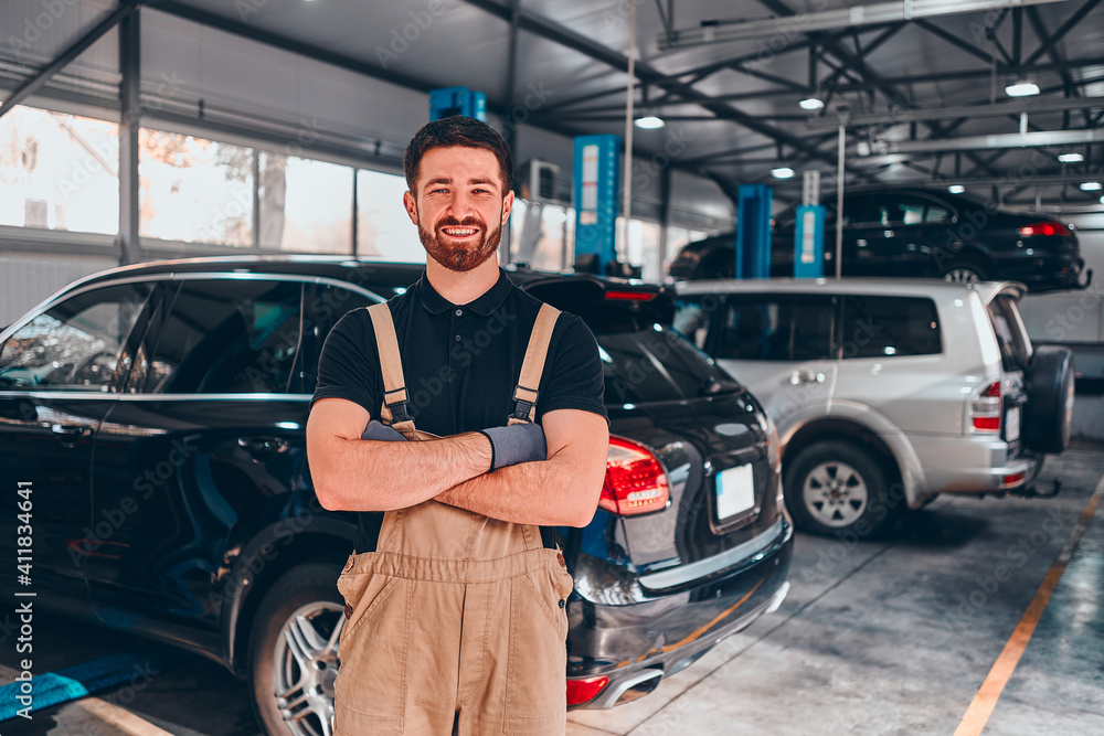 Auto mechanic with crossed arms smiling in his garage. Auto mechanic with crossed arms smiling in his garage.
