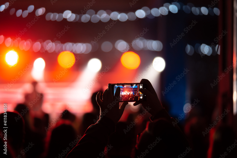 Person close up of recording video with smartphone during a concert. Person close up of recording video with smartphone during a concert.