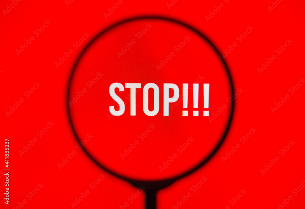 Word stop on red screen through magnifying glass. Word stop on red screen through magnifying glass.